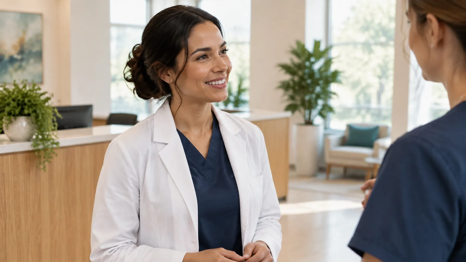 A clinician and colleague talking in a bright practice reception.